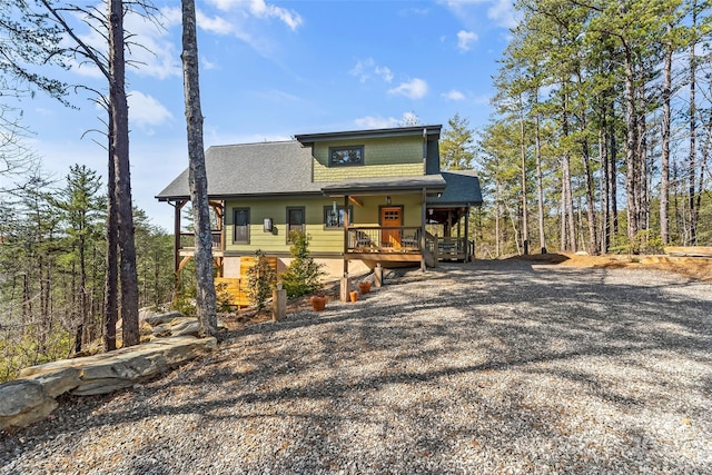 chalet / cabin featuring a porch, gravel driveway, and a shingled roof