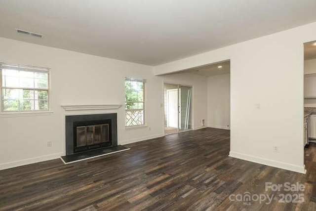 unfurnished living room with a healthy amount of sunlight and dark wood-type flooring