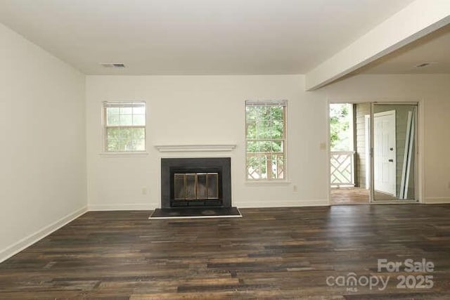 unfurnished living room with beamed ceiling, dark hardwood / wood-style floors, and a wealth of natural light