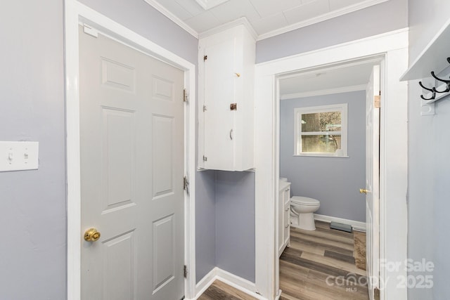 bathroom with hardwood / wood-style flooring, crown molding, and toilet