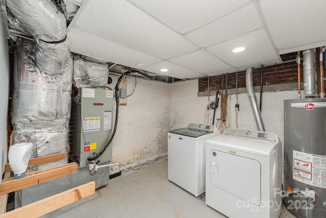 clothes washing area featuring brick wall, independent washer and dryer, water heater, and heating unit