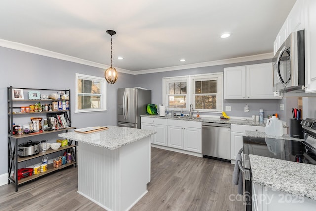 kitchen featuring stainless steel appliances, light stone countertops, white cabinets, decorative light fixtures, and a kitchen island