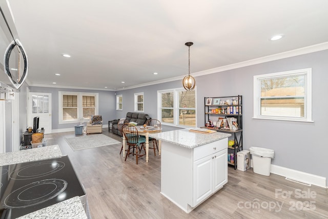 kitchen featuring decorative light fixtures, light hardwood / wood-style floors, white cabinetry, and crown molding