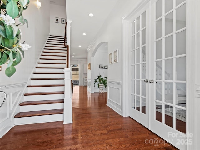 foyer entrance with stairs, recessed lighting, wood finished floors, arched walkways, and a decorative wall