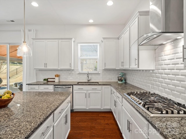 kitchen featuring white cabinetry, wall chimney exhaust hood, appliances with stainless steel finishes, and a sink