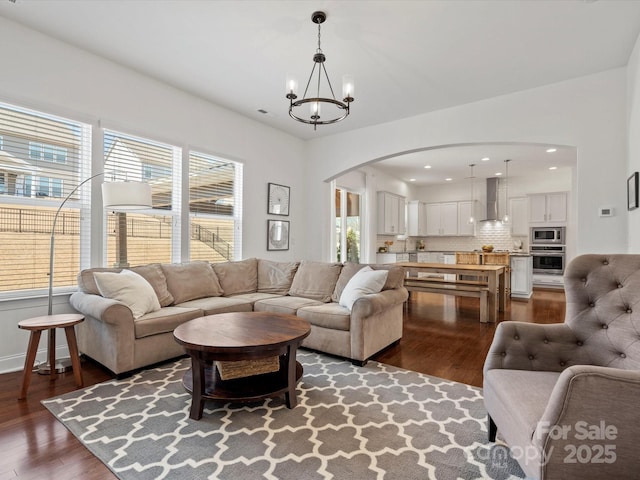 living room featuring a notable chandelier, dark wood-type flooring, and a healthy amount of sunlight