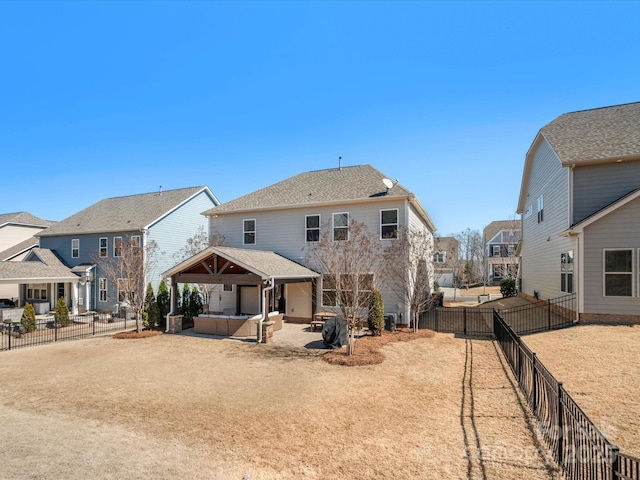 back of property with a gazebo, a patio, a fenced backyard, and a hot tub