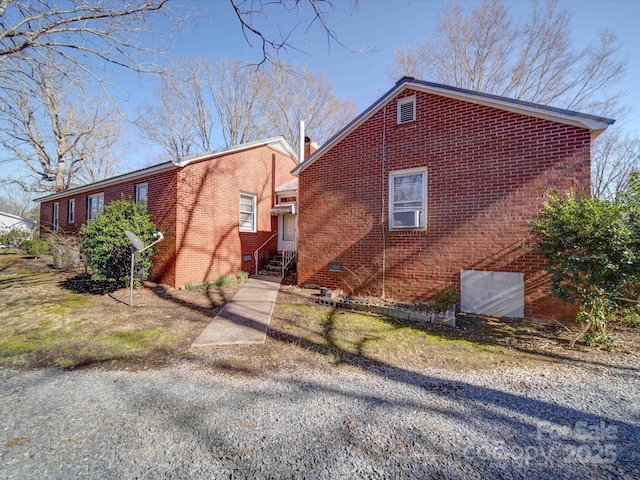 exterior space with crawl space, a chimney, and brick siding