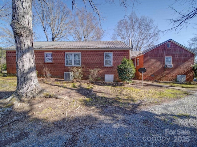 view of side of home with crawl space, metal roof, cooling unit, and brick siding