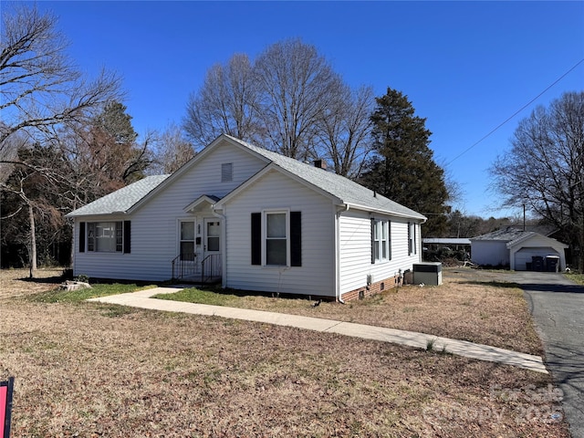 view of front of home featuring a garage, an outdoor structure, a front yard, and central air condition unit