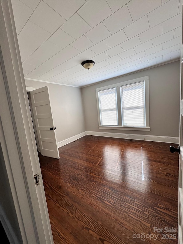 unfurnished room with crown molding and dark wood-type flooring