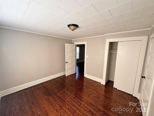 unfurnished bedroom featuring crown molding, dark hardwood / wood-style flooring, and a closet