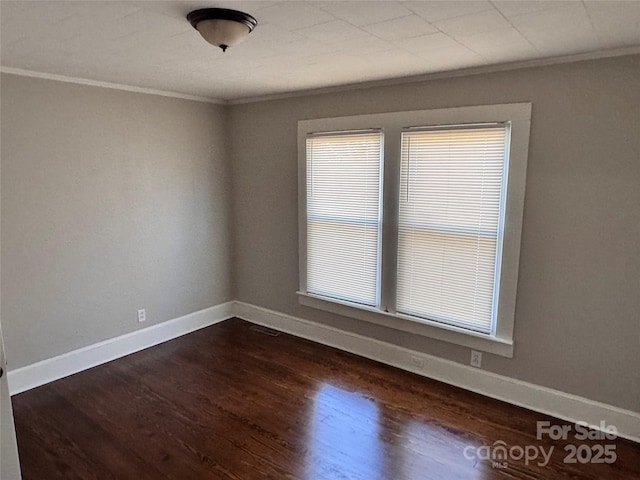 empty room featuring dark wood-type flooring and ornamental molding