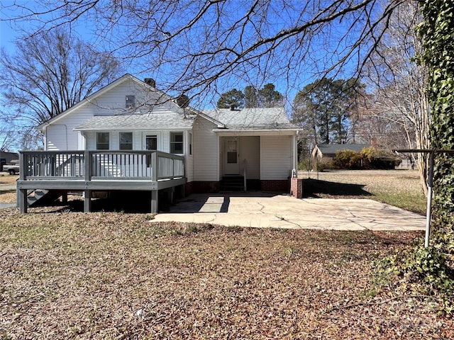 back of property with a wooden deck and a patio