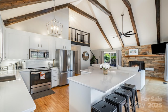 353 Whippoorwill Rd, Mooresville, NC 28117 - kitchen with appliances with stainless steel finishes, high vaulted ceiling, light countertops, a breakfast bar area, and light wood-type flooring