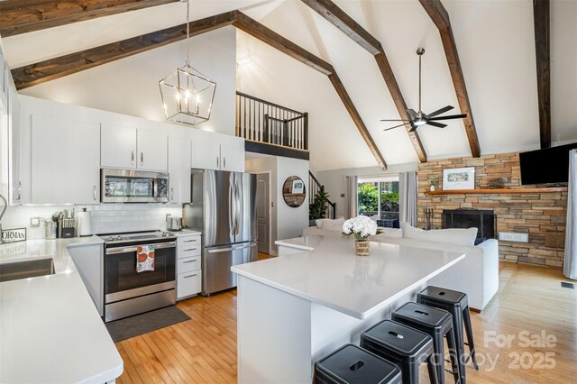 353 Whippoorwill Rd, Mooresville, NC 28117 - kitchen featuring appliances with stainless steel finishes, high vaulted ceiling, light countertops, a kitchen bar, and light wood finished floors