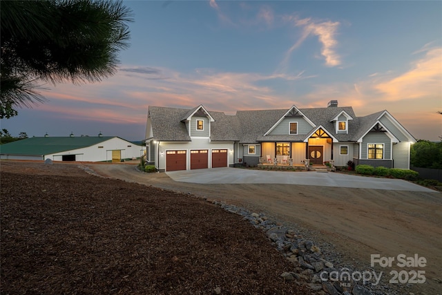 modern farmhouse with an attached garage, a shingled roof, driveway, and a chimney
