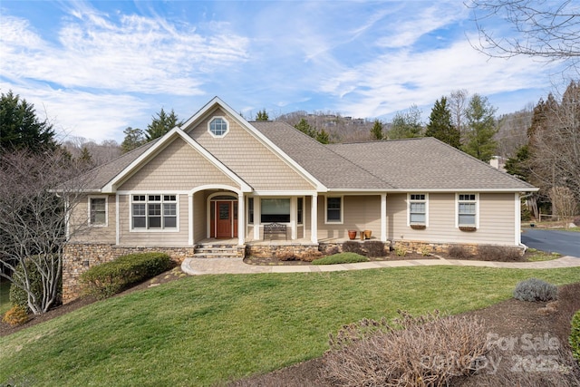 view of front facade featuring a porch, a front yard, and a shingled roof