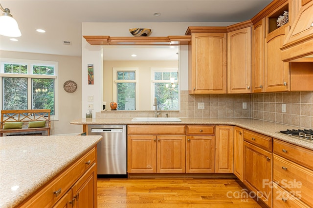 kitchen with light wood-style flooring, a sink, appliances with stainless steel finishes, a wealth of natural light, and decorative light fixtures