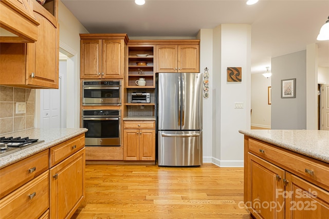 kitchen with appliances with stainless steel finishes, brown cabinets, light wood-style floors, open shelves, and backsplash