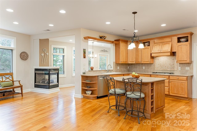 kitchen featuring appliances with stainless steel finishes, a kitchen breakfast bar, a center island, light wood-type flooring, and open shelves