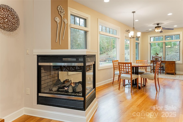 dining area featuring wood finished floors, recessed lighting, a multi sided fireplace, and baseboards