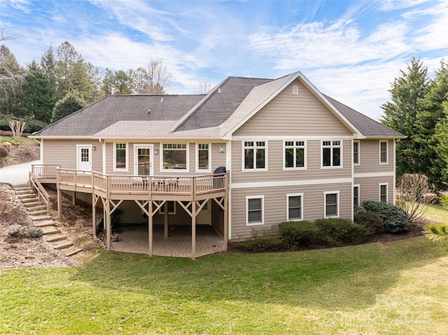 back of house with a shingled roof, a yard, a wooden deck, and stairs