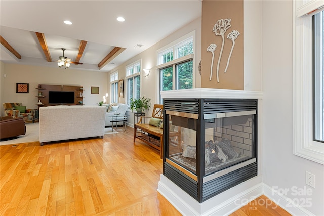 living room with baseboards, wood finished floors, a multi sided fireplace, beam ceiling, and recessed lighting