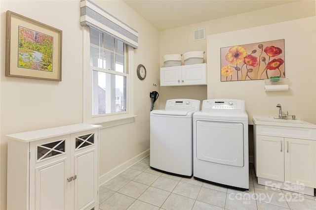 clothes washing area featuring light tile patterned floors, washing machine and dryer, a sink, visible vents, and cabinet space