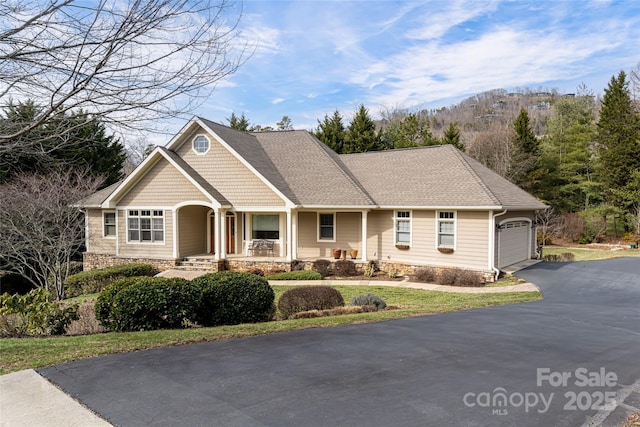 craftsman house with driveway, an attached garage, a porch, and roof with shingles