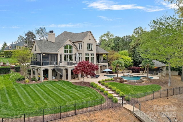 rear view of house with a fenced backyard, a sunroom, a lawn, a chimney, and a patio area