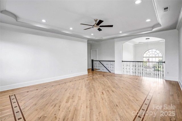 unfurnished living room featuring crown molding, a raised ceiling, visible vents, and light wood-style floors