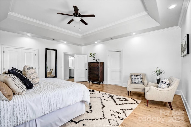 bedroom featuring recessed lighting, a raised ceiling, crown molding, and wood finished floors