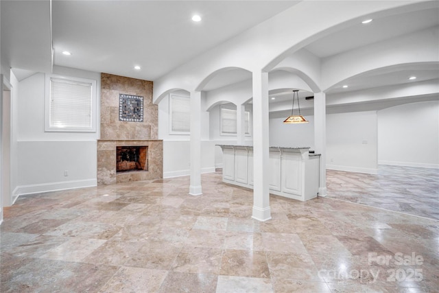 unfurnished living room with recessed lighting, baseboards, and a tiled fireplace