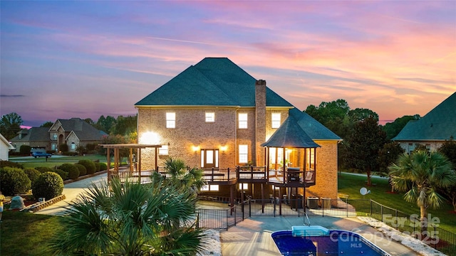 rear view of property with a chimney, fence, a patio, and brick siding