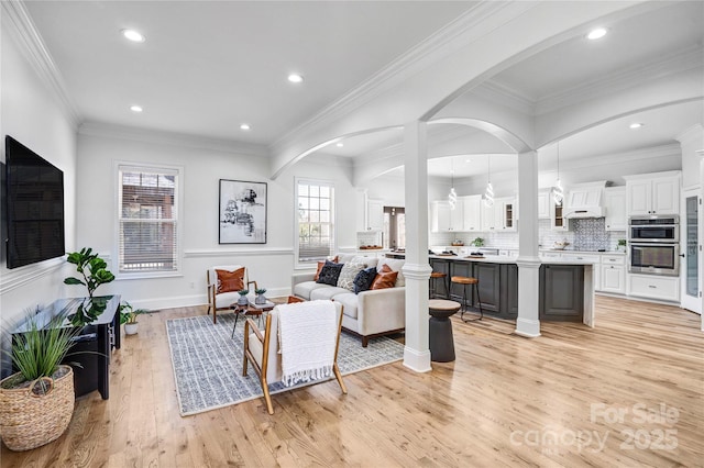 living area with light wood-style floors, recessed lighting, crown molding, and baseboards