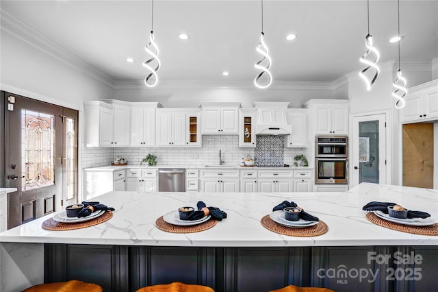 kitchen featuring hanging light fixtures, appliances with stainless steel finishes, a kitchen bar, and glass insert cabinets