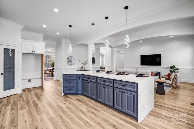 kitchen featuring white cabinets, open floor plan, light stone countertops, blue cabinetry, and pendant lighting