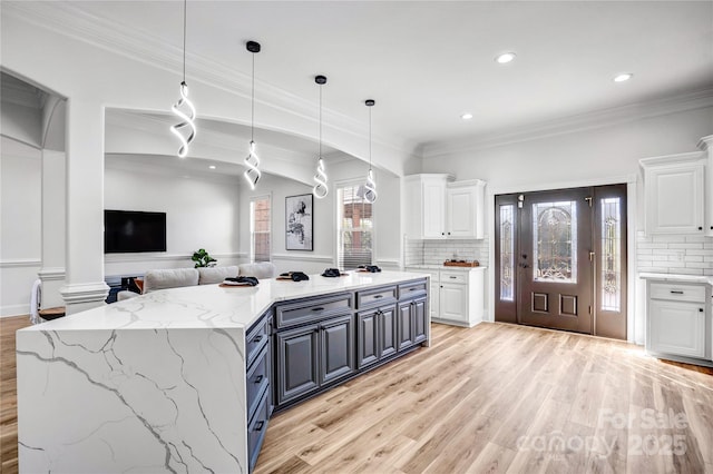 kitchen featuring light stone countertops, light wood-style flooring, white cabinetry, and open floor plan