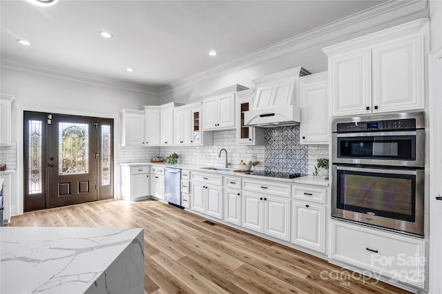 kitchen featuring stainless steel appliances, white cabinetry, a sink, and under cabinet range hood