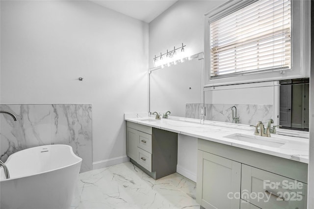 full bathroom with a freestanding tub, a sink, marble finish floor, and double vanity