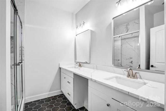 full bath with double vanity, a sink, a marble finish shower, and baseboards