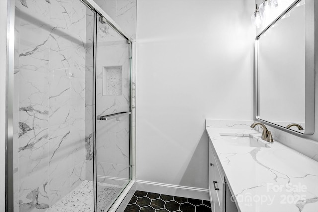 full bathroom featuring a marble finish shower, baseboards, and vanity