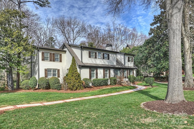 view of front of property with brick siding, a chimney, and a front yard