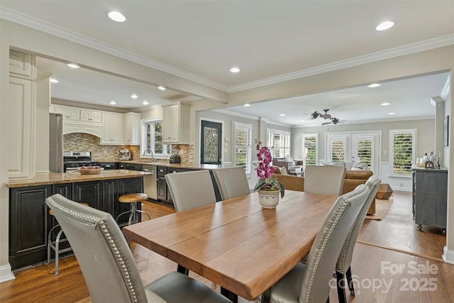 dining space with baseboards, recessed lighting, light wood-type flooring, and crown molding