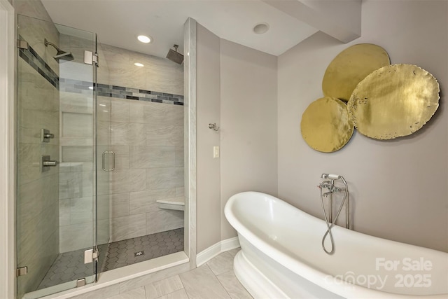 bathroom featuring recessed lighting, a freestanding bath, a shower stall, and baseboards