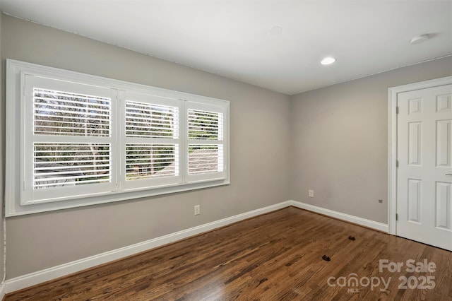 spare room featuring recessed lighting, dark wood-style flooring, and baseboards