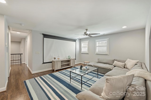 living area with a ceiling fan, attic access, dark wood-style flooring, and baseboards