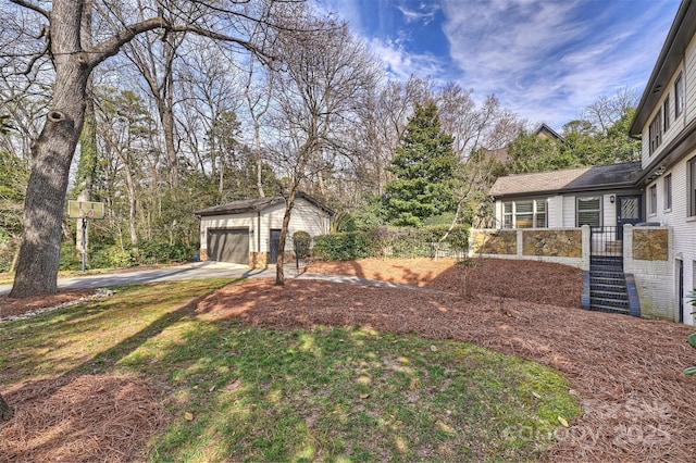 view of yard featuring an outdoor structure, a detached garage, and fence