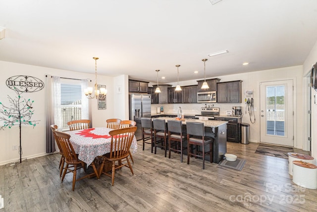 dining space featuring a chandelier, recessed lighting, baseboards, and wood finished floors